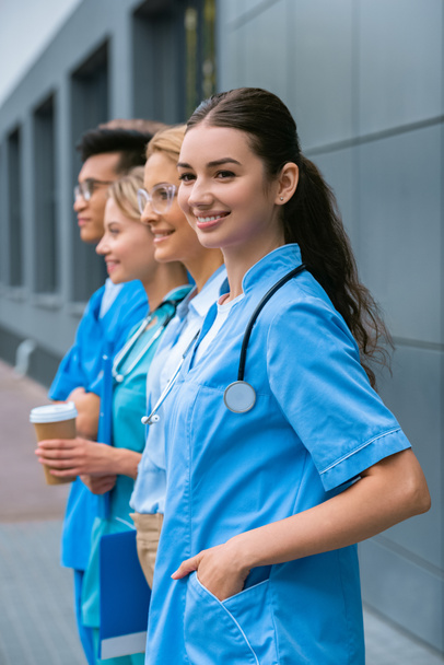 боковой вид преподавателя и счастливых студентов-мультикультуралистов, стоящих в очереди возле медицинского университета
 - Фото, изображение