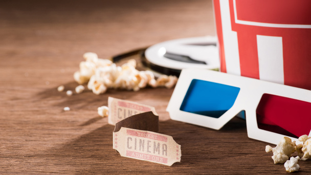 close up view of paper bucket with popcorn, retro cinema tickets and 3d glasses on wooden tabletop - Photo, Image