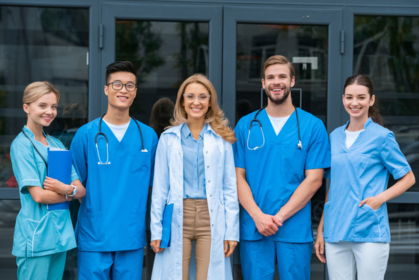 profesor sonriente y estudiantes multiculturales mirando a la cámara en la universidad médica
 - Foto, imagen