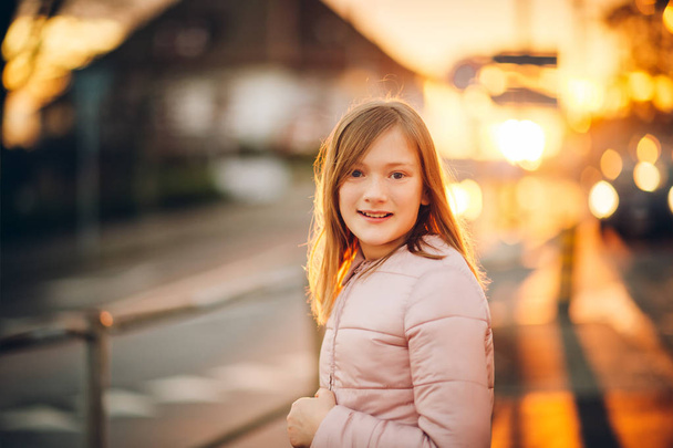 Outdoor Portret van een schattig klein preteen meisje in de zonsondergang licht - Foto, afbeelding