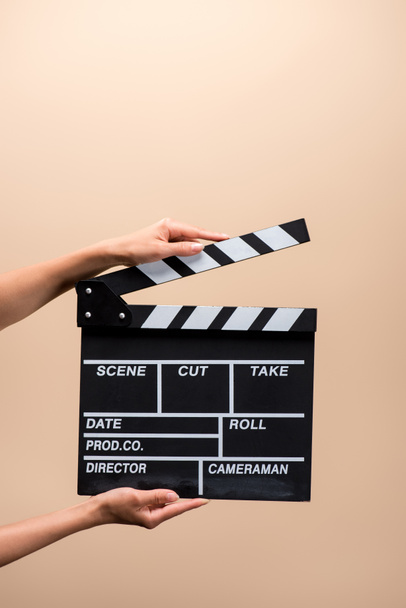 partial view of woman holding clapper board in hands isolated on beige - Photo, Image