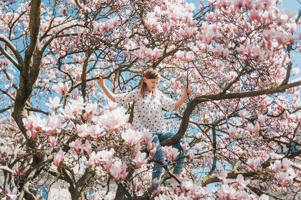 Menina criança feliz jogando na árvore de magnólia na primavera
 - Foto, Imagem