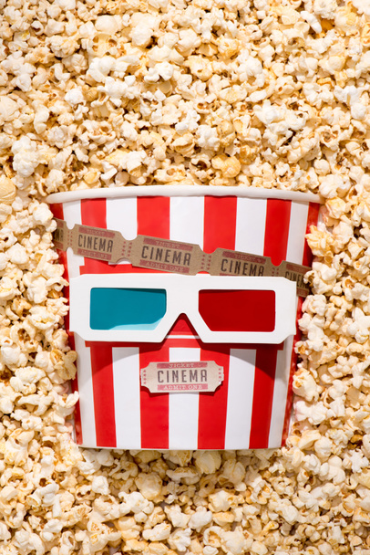 flat lay with arrangement of disposable bucket with popcorn, retro cinema tickets and 3d glasses - Fotografie, Obrázek