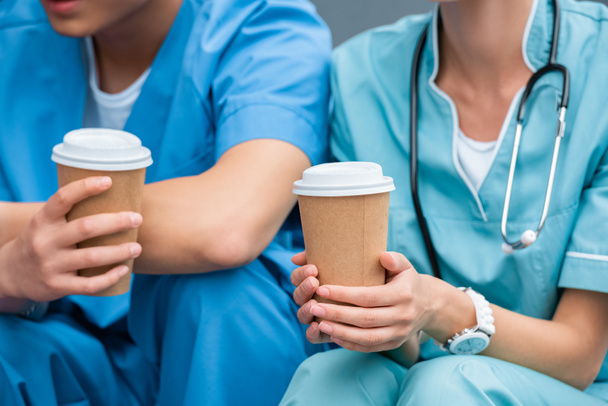 imagen recortada de estudiantes de medicina sosteniendo tazas de café desechables
 - Foto, Imagen