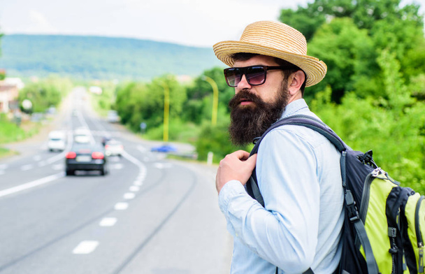 Adventure spirit. Hitchhiker try to stop transport to get to destination. Man at edge of highway looking for transport. Hitchhiking means transportation gained asking strangers for ride in their car - 写真・画像