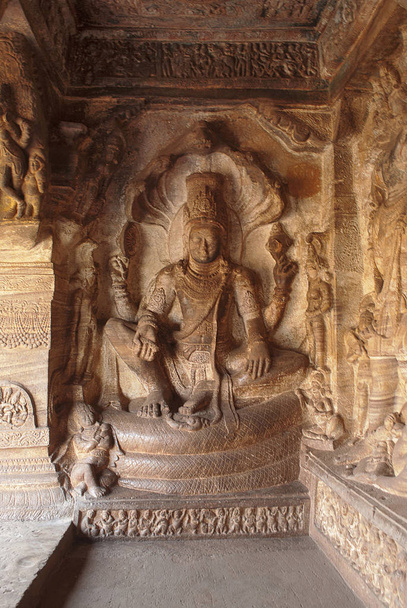 Cueva 3: Figuras talladas de Vishnu sentadas en una serpiente encapuchada llamada Sesha o Ananta en el lado oriental de la veranda. Cuevas de Badami, Karnataka, India
.  - Foto, imagen