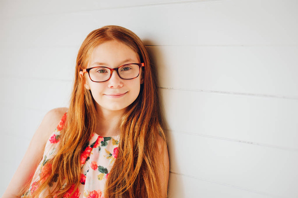 Portrait of adorable preteen kid girl of 10-11 yers old with long red hair, wearing eyeglasses - Photo, Image