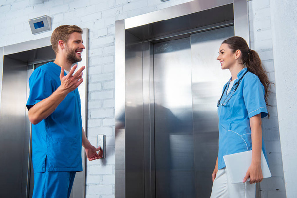 medical students talking while waiting elevator in university - 写真・画像
