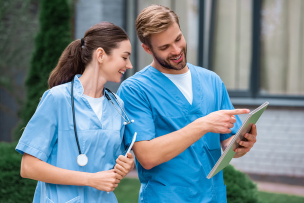 handsome medical student pointing on something in notebook to friend on street - Photo, Image