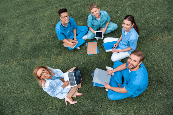 vista aerea di insegnante che ha lezione con gli studenti multiculturali presso l'università medica su erba verde
 - Foto, immagini