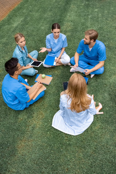 vista ad alto angolo di insegnante che ha lezione con studenti multietnici presso l'università medica su erba verde
 - Foto, immagini