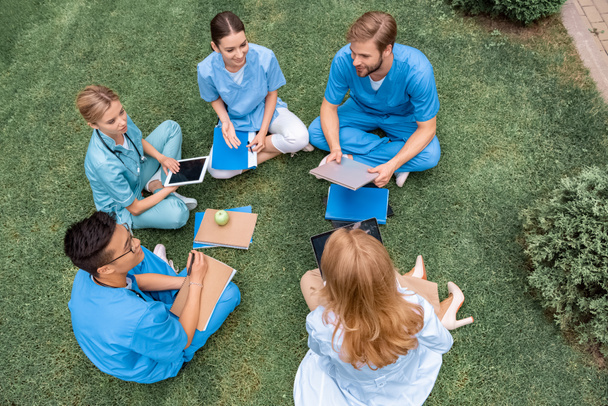 Blick aus der Vogelperspektive auf Lehrer, die Unterricht mit multikulturellen Studenten an der medizinischen Universität auf grünem Gras haben - Foto, Bild