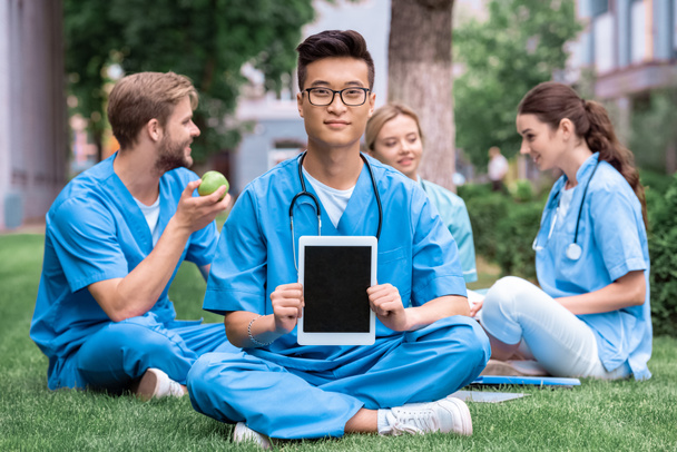 schöner asiatischer Medizinstudent hält Tablet mit leerem Bildschirm - Foto, Bild