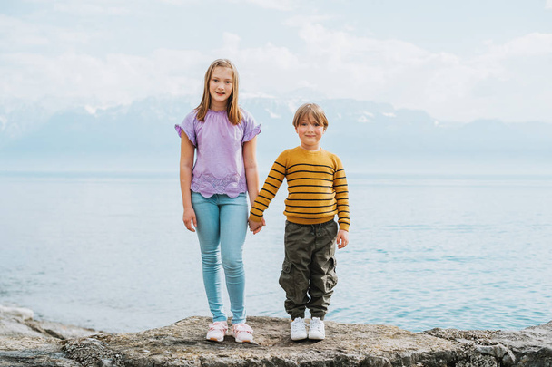 Cute kids playing by the lake, holding hands, little brother and sister portrait - Foto, Imagen