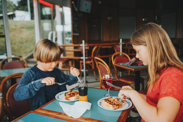 Двое детей едят кроке-мсье в ресторане, традиционные французские тосты с ветчиной и сыром
 - Фото, изображение