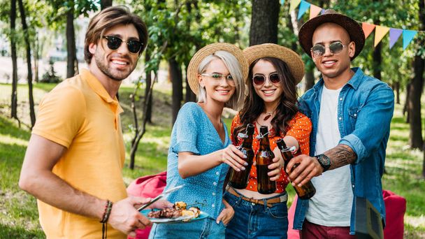 portrait of young multiethnic friends having barbecue in summer park - 写真・画像