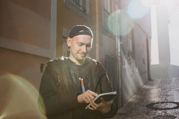 Nuori mies turisti kadulla käyttää tabletin tarkastella hakemuksen karttoja alueen tai soittaa taksin tai jotain muuta
 - Valokuva, kuva