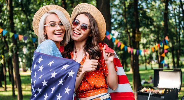 Portret van gelukkig vrouwen met Amerikaanse vlag in park - Foto, afbeelding
