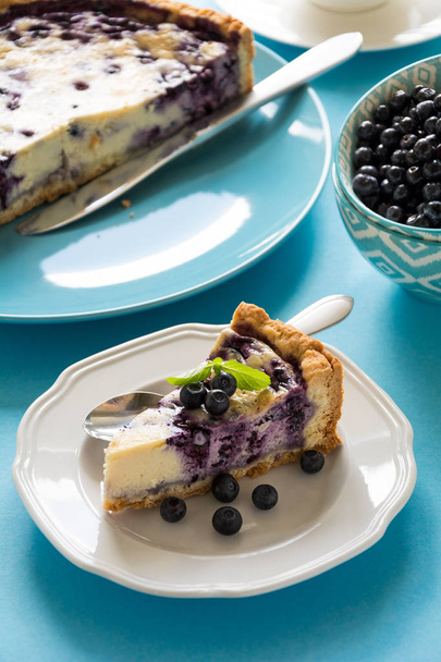 Tea time. Homemade blueberry cheesecake with ricotta cheese on blue paper background - Foto, immagini