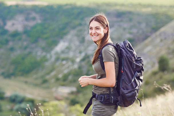 Girl tourist with a backpack smiling in the nature. - Foto, imagen