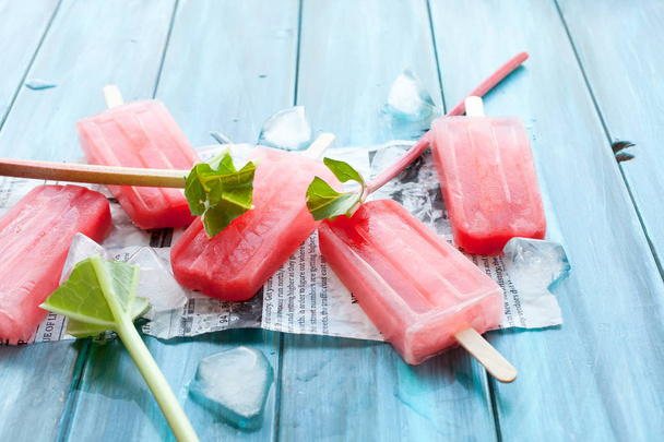 Refreshing rhubarb popsicles on blue wooden background with newspaper article - Foto, Bild