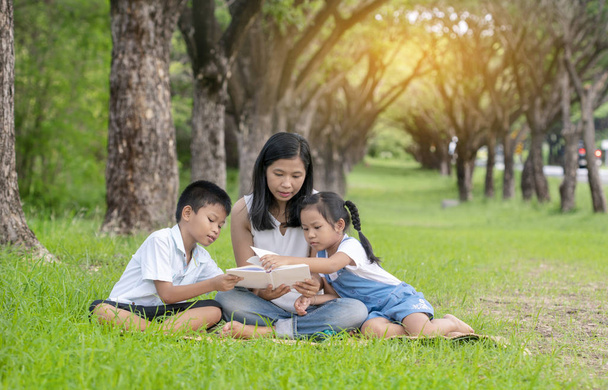 Asian family, mother, son and daughter doing reading activities at the park. - Fotografie, Obrázek