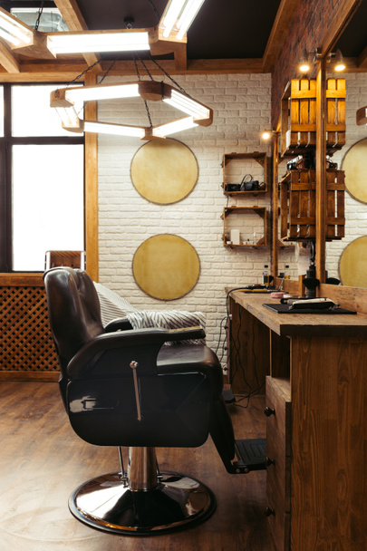 leerer Stuhl, Spiegel und Lampen im modernen Friseursalon-Interieur - Foto, Bild