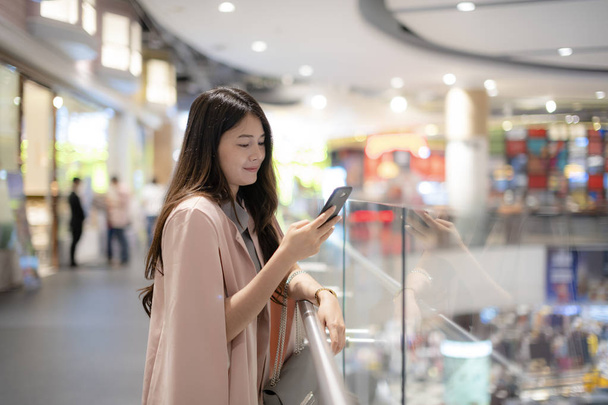 Asian women check cell phone data in shopping mall - Photo, Image