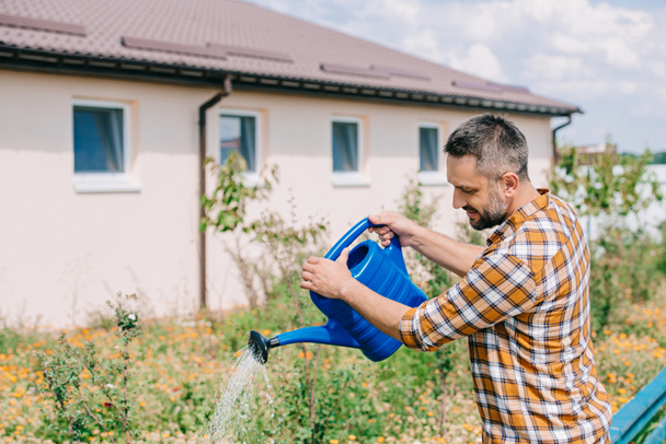 handsome middle aged farmer watering plants in garden  - Fotografie, Obrázek