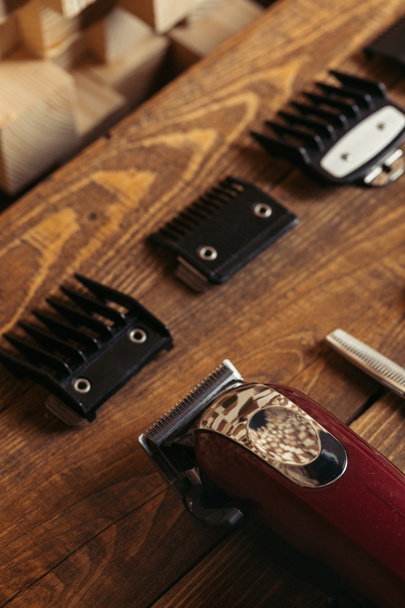 vista ravvicinata di clipper elettrico con vari ugelli su ripiano in legno in barbiere
 - Foto, immagini