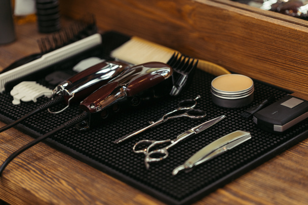Крупный план комплекта профессиональных парикмахерских инструментов на деревянной полке в парикмахерской
 - Фото, изображение