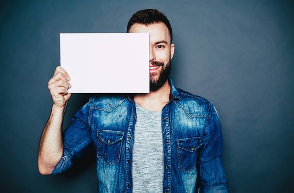 Beard man holding blank sheet of paper over grey background - Foto, Bild