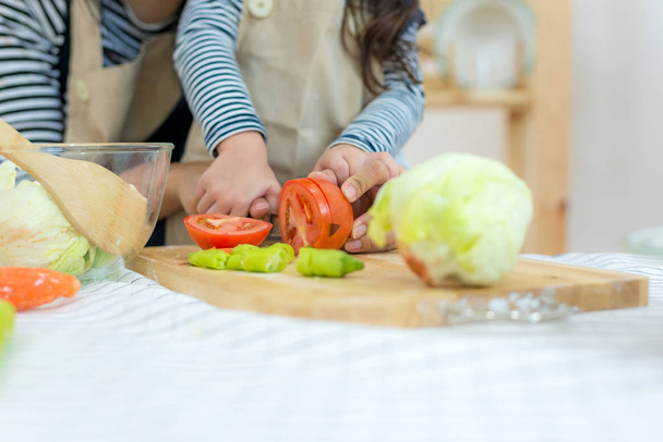 Close up hands mother and kid girl cooking and cutting vegetables on kitchen.  Lifestyle Concept - Фото, зображення