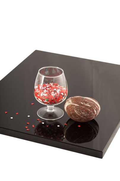 Φυσική πέτρα και ένα ποτήρι στην λουστραρισμένο επικάλυψη, την αντανάκλαση των αντικειμένων. - Φωτογραφία, εικόνα