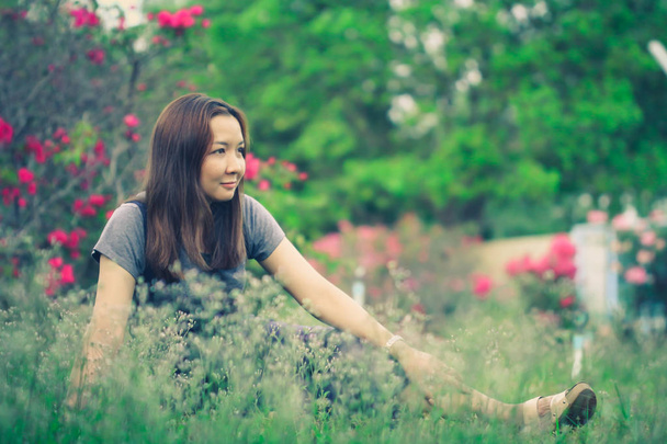 Gevşeme bir ruh hali ile bir çayırda oturan güzel kadın. - Fotoğraf, Görsel