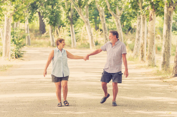 Happy senior couple in love walking and holding hands in the park - 写真・画像