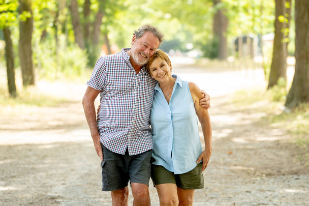 Feliz pareja de ancianos enamorados caminando y abrazándose en el parque
. - Foto, imagen
