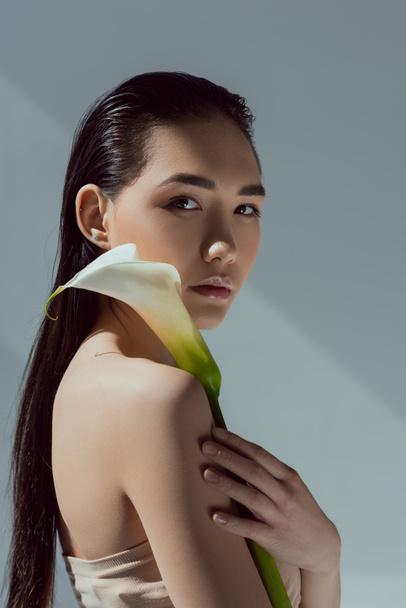 attractive asian woman with calla flower, isolated on grey - Fotoğraf, Görsel