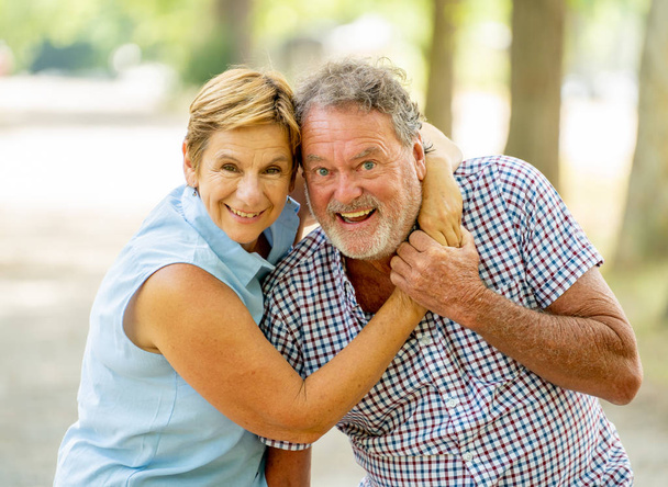 Heureux couple de personnes âgées souriantes amoureux se détendre, embrasser et s'amuser dans le parc
. - Photo, image