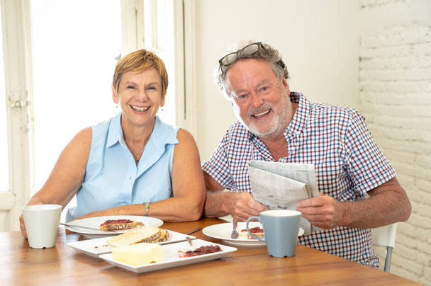Attractive mature retired couple having breakfast together at home - Foto, afbeelding
