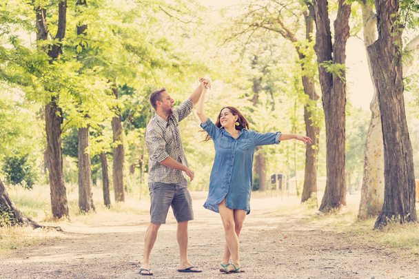 Happy couple dancing and having fun together in a beautiful green park - 写真・画像