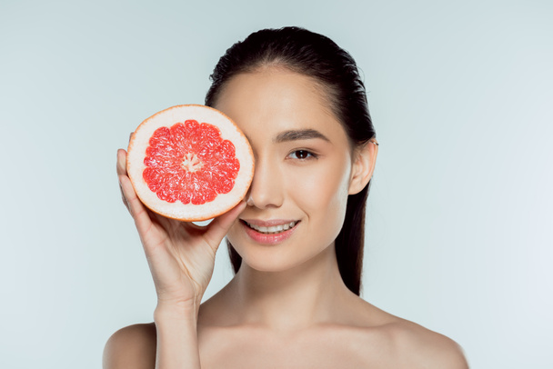 attractive asian girl posing with grapefruit, isolated on grey - Valokuva, kuva