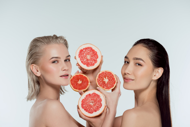 обнаженные многоэтнические женщины, позирующие с половинками грейпфрута, изолированные на сером, концепция ухода за кожей
 - Фото, изображение