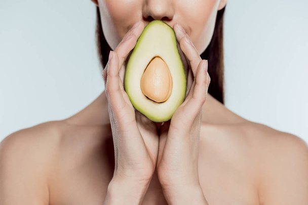 cropped view of naked girl posing with natural avocado, isolated on grey - Fotografie, Obrázek