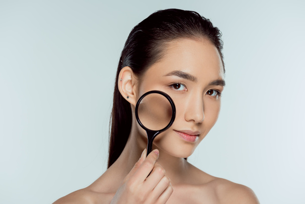 Krásná Asiatka s čistou kůži hospodářství Lupa, kůže péče o konceptu, izolované Grey - Fotografie, Obrázek