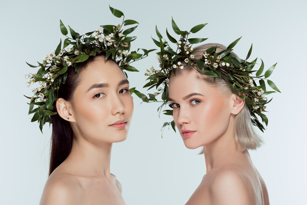 naked multiethnic girls in floral wreaths, isolated on grey - Фото, изображение
