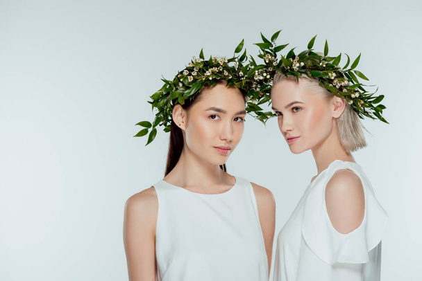 multicultural women posing in floral wreaths, isolated on grey - Foto, immagini