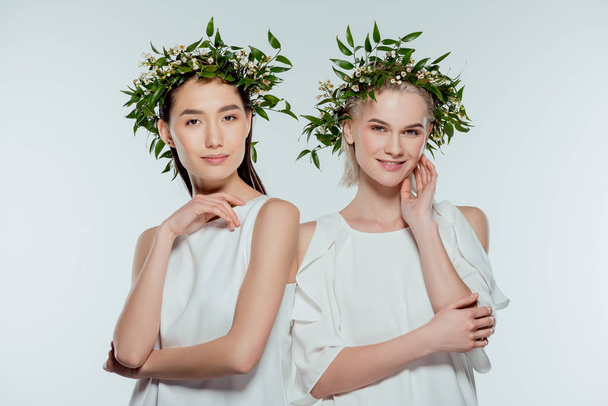 azjatyckiej i kaukaskiej girls stwarzających w zielonych kwiatów wieńce, na szarym tle - Zdjęcie, obraz