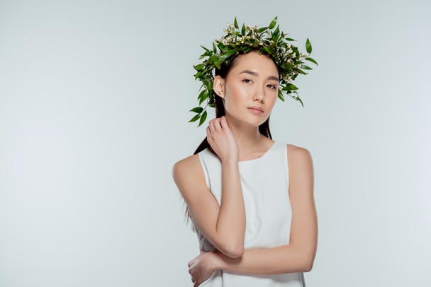 beautiful asian girl posing in floral wreath, isolated on grey - Photo, Image