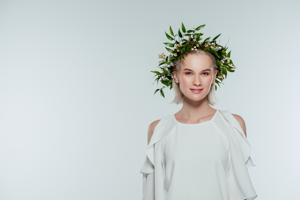 attractive fashionable young woman posing in floral wreath, isolated on grey - Foto, imagen
